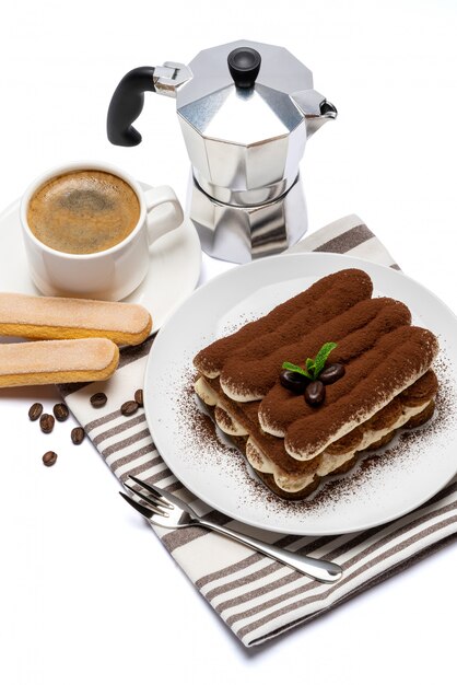 Postre clásico tiramisú en plato de cerámica, galletas savoiardi y taza de café aislado en la superficie blanca con trazado de recorte