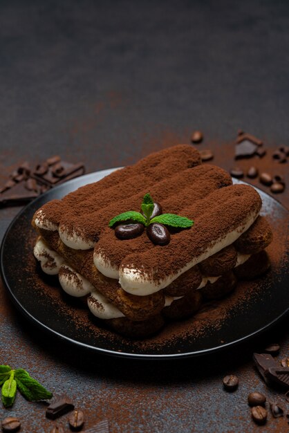 Postre clásico tiramisú en plato de cerámica sobre hormigón