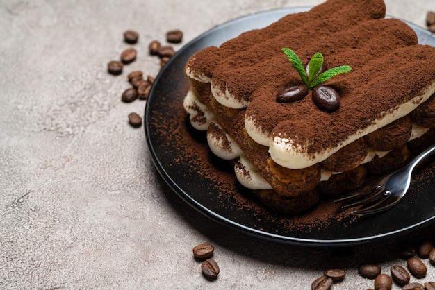 Postre clásico tiramisú en plato de cerámica sobre hormigón