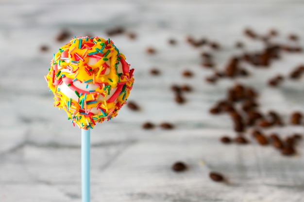 Postre colorido en un palo. Frijoles de color marrón oscuro. Cake pop y granos de café. Azúcar o cafeína.