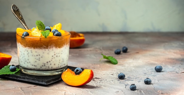 Postre de cuajada o yogur con melocotones, arándanos y chía Postre casero con lugar de frutas para la vista superior del texto