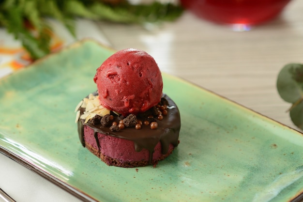 Postre con una cucharada de helado de bayas en una mesa de madera con decoración de flores