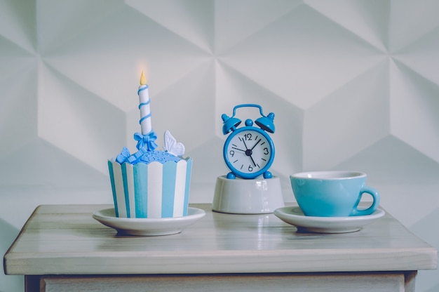 Postre de cumpleaños cupcake con despertador azul y taza de té