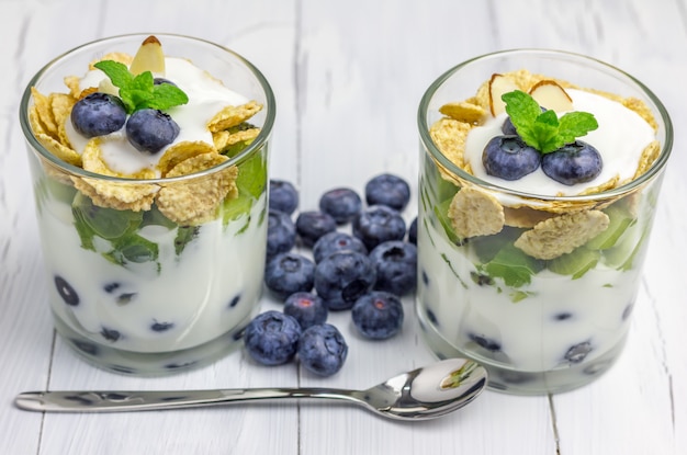 Postre delicioso yogur con arándanos, kiwi y cereales en el vaso