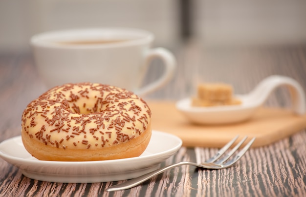 Postre donas y taza de café caliente en la mesa de madera