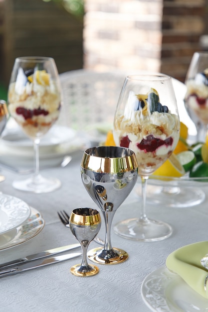 Postre dulce en vasos grandes en la mesa servida para banquetes de bodas