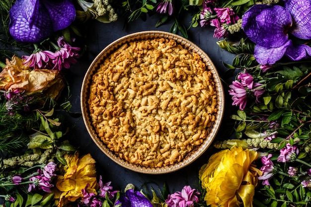 Postre de la empanada de manzana de la vainilla y flores brillantes en fondo gris.