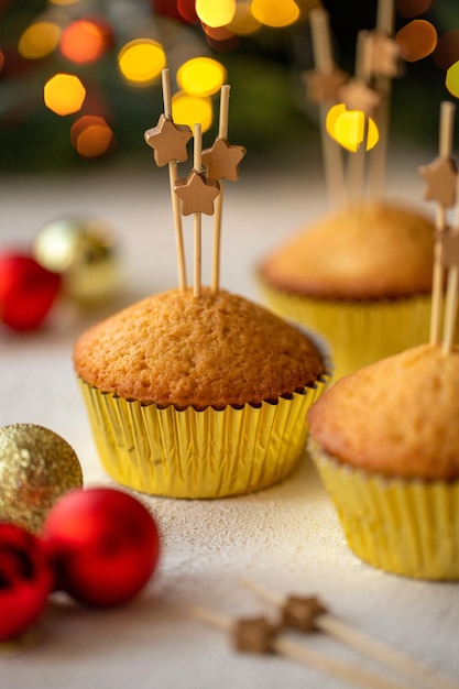 Postre festivo de Año Nuevo. Cupcakes decorados con estrellas de madera en brochetas sobre una mesa blanca.