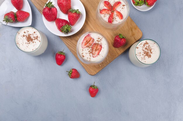 Postre de fresa en un frasco de vidrio con fresas frescas sobre una mesa gris con servilleta de lino