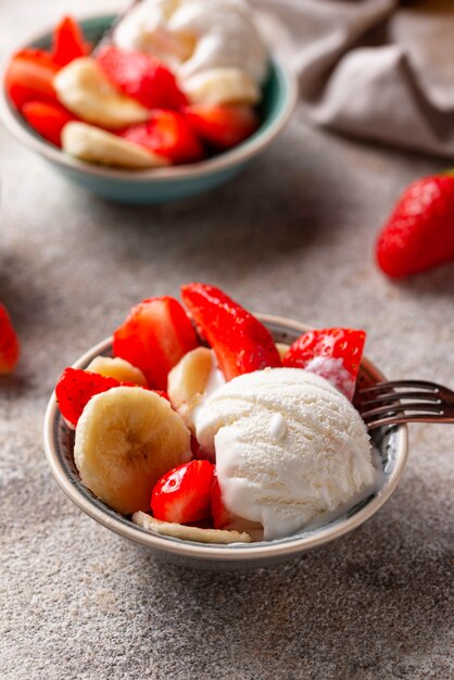 Postre de fresa, plátano y helado.