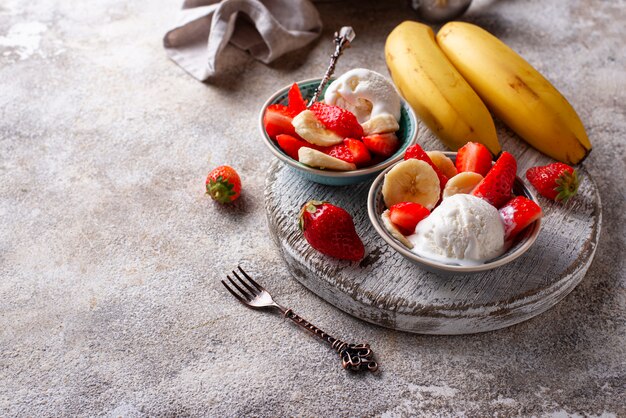 Postre de fresa, plátano y helado.