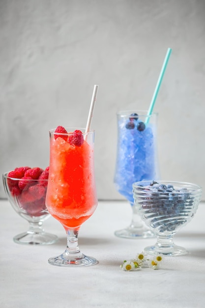 Foto postre de granito siciliano de verano, jugo de arándanos y frambuesas congelados en grandes vasos de vidrio en una b blanca