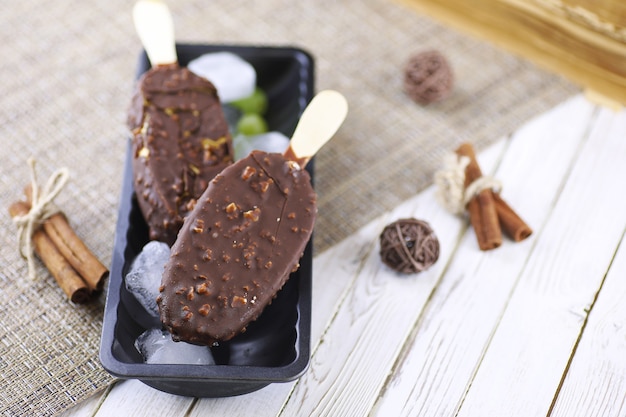 Postre helado de chocolate con nueces en un palo de madera