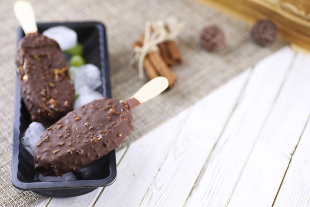 Postre helado de chocolate con nueces en un palo de madera