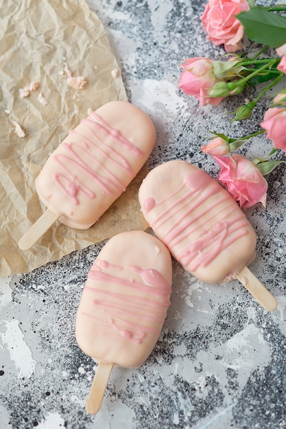 Foto postre de helado gourmet con sabor a coco glaseado de chocolate glaseado de chocolate rosa de una panadería casera sobre fondo gris.