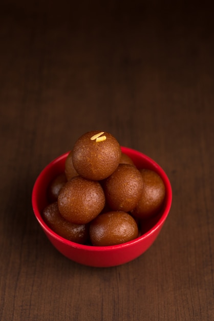 Foto postre indio o plato dulce gulab jamun en un recipiente en la oscuridad.