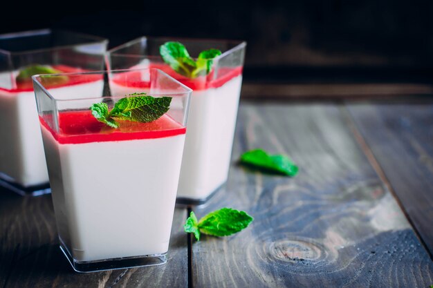 El postre italiano Panna Cotta con salsa de frambuesa se sirve para tres en pequeños vasos transparentes