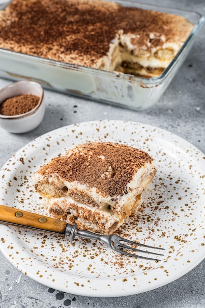 Postre italiano tiramisú cubierto con cacao en un plato. Fondo gris. Vista superior.