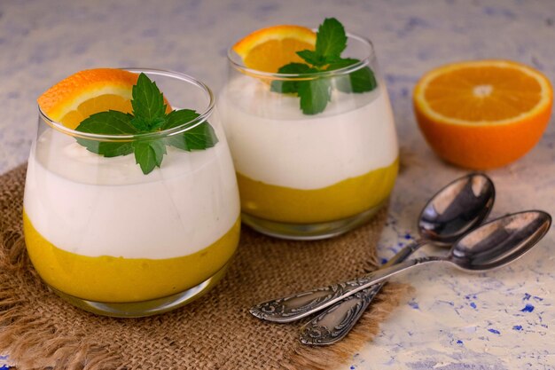 Postre con mascartone y cuajada de naranja en vasos sobre un fondo de mármol blanco