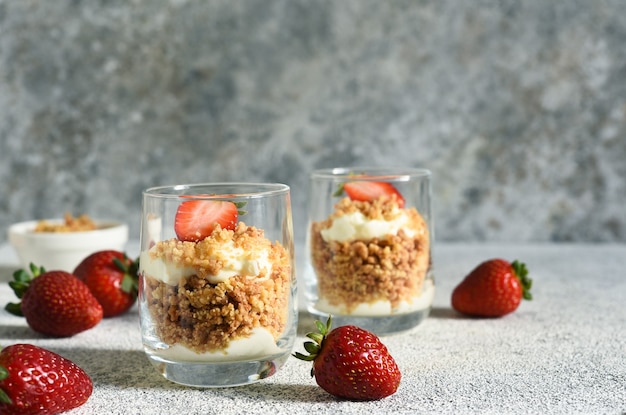 Postre con migas, nata y fresas. Tarta de queso en un vaso.