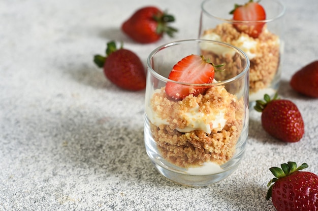 Postre con migas, nata y fresas. Tarta de queso en un vaso.