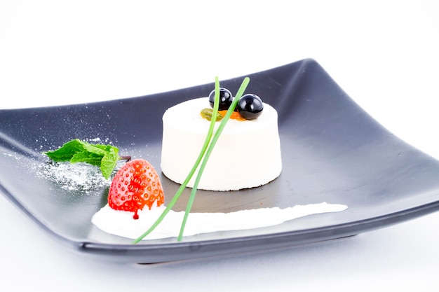 Postre de mousse de vainilla en plato negro cuadrado con arándanos