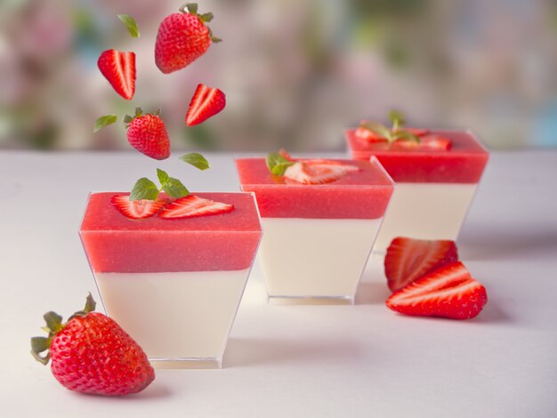 Postre panna cotta con fresas frescas volando sobre la naturaleza