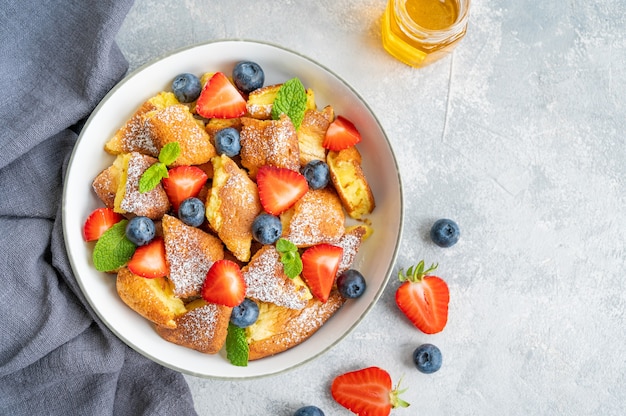 Postre de panqueques austriaco tradicional Kaiserschmarrn con bayas frescas y azúcar en polvo