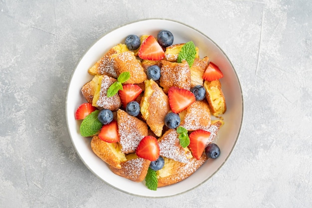 Postre de panqueques austriaco tradicional Kaiserschmarrn con bayas frescas y azúcar en polvo