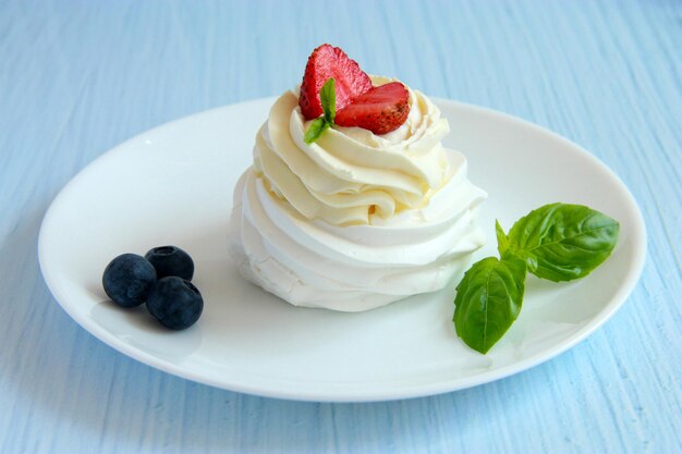 Postre Pavlova casero: merengue con crema batida, menta y bayas frescas en el plato