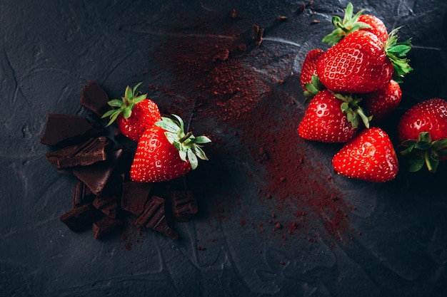 Postre preparando fresas en chocolate con cacao sobre un fondo oscuro Vista superior