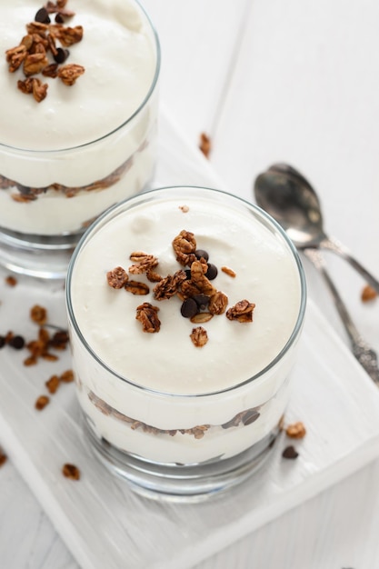 Postre con queso mascarpone y granola sobre un fondo blanco de madera