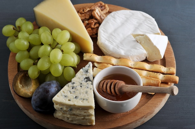 Postre de queso, palitos de pan, miel, nueces y uvas