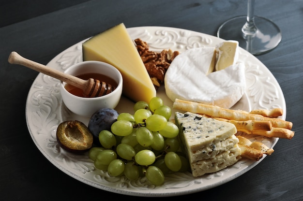 Postre de queso, palitos de pan, miel, nueces y uvas