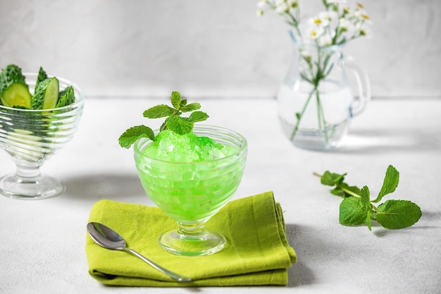 Postre refrescante de verano de hielo picado, pepino congelado y jugo de menta aislado sobre fondo blanco.