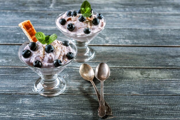 Postre del requesón con los arándanos y las rebanadas de las galletas vienesas en una taza de cristal.