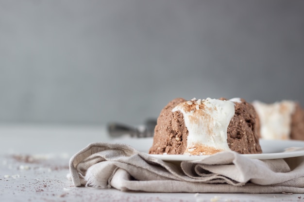 Postre de requesón decorado con glaseado de chocolate blanco, hojuelas de coco y cacao en polvo