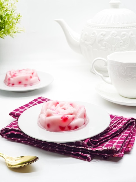 Un postre rosa y blanco con una tetera sobre la mesa.