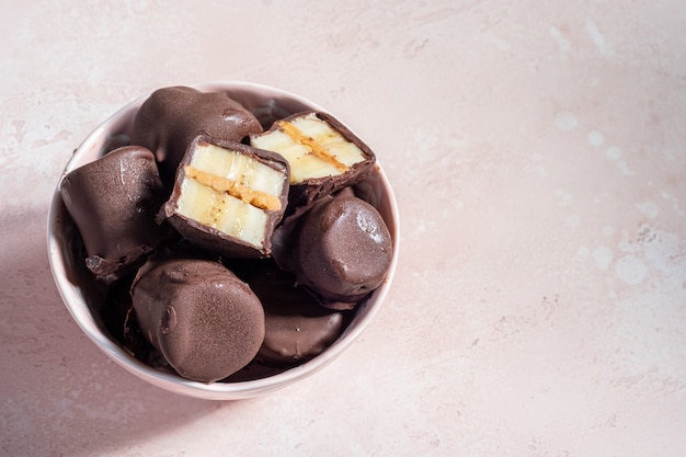 Postre saludable congelado. Bocaditos de plátano con mantequilla de maní y chocolate amargo