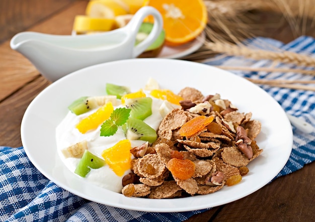 Un postre saludable con muesli y fruta en un plato blanco en la mesa