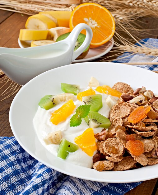 Postre saludable con muesli y fruta en un plato blanco sobre la mesa