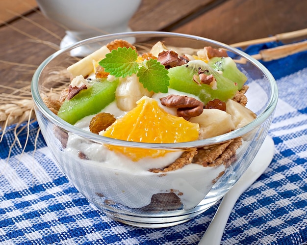 Un postre saludable con muesli y fruta en un tazón de vidrio en la mesa