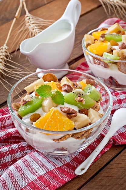 Un postre saludable con muesli y fruta en un tazón de vidrio en la mesa