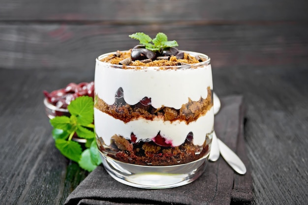 Postre Selva Negra de cerezas, galleta de chocolate y requesón suave con crema en un vaso sobre servilleta