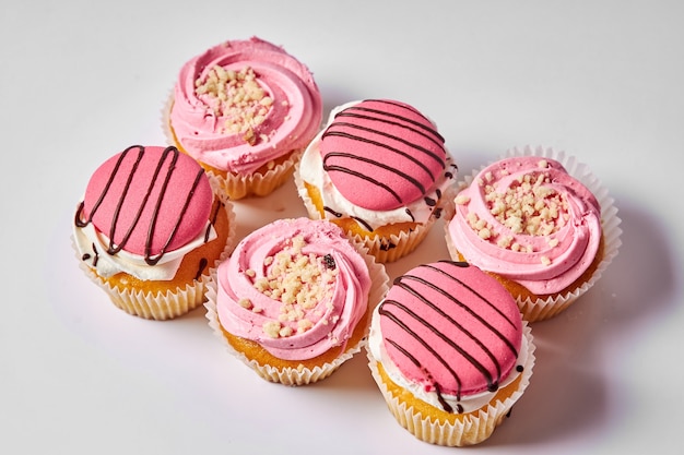 Postre de tarta deliciosos muffins con crema rosa Dulce Juego de tortas sobre un fondo blanco.