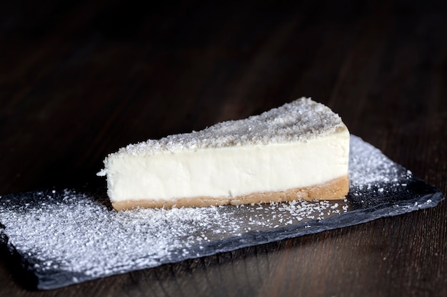 Postre de tarta de queso cubierta con pulpa de coco seca, tarta de queso en bandeja individual espolvoreada con azúcar en polvo