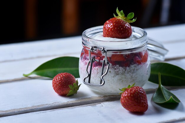 Postre de tarta de queso de fresa en un frasco sobre la mesa