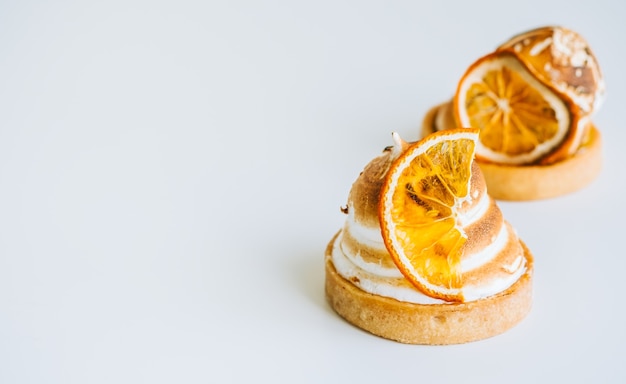 Postre de tartaleta de limón con merengue sobre fondo blanco con espacio de copia.