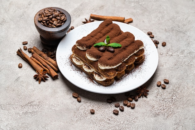 Foto postre tiramisú clásico en placa de cerámica sobre mesa de hormigón