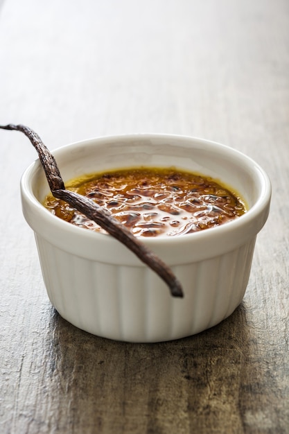 Postre tradicional francés creme brulée con azúcar caramelizada encima, sobre mesa de madera